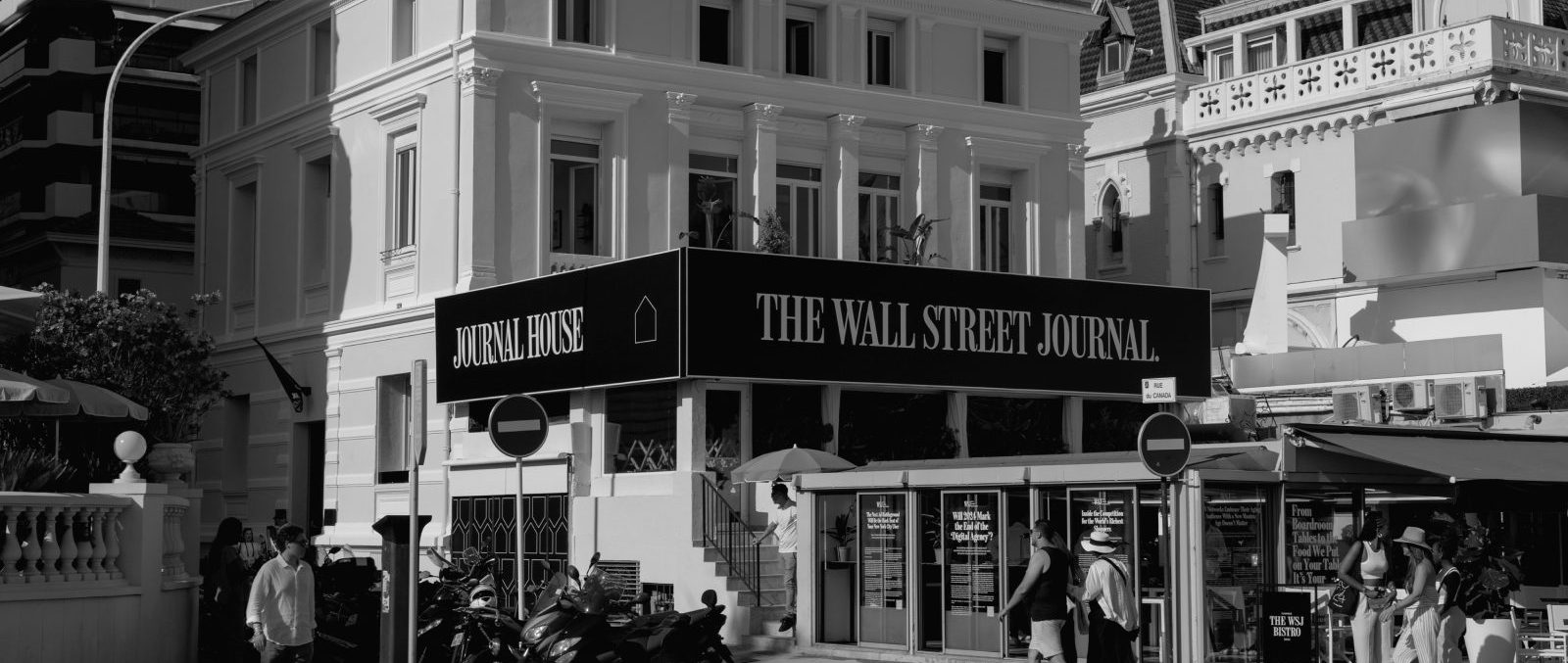 Neighborhood, Intersection, Road, Accessories, Bag, Handbag, Person, Clothing, Footwear, Shoe, City, Street, Urban, Hat, Path, Motorcycle, Transportation, Vehicle, Road Sign, Sign, Symbol, Bicycle, Architecture, Building, Cycling, Sport, Machine, Wheel, Sidewalk