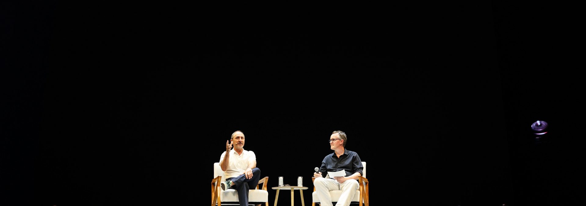 Chair, Furniture, Stage, Person, Clothing, Footwear, Shoe, Crowd, Accessories, Glasses, Desk, Table, Cup, Audience